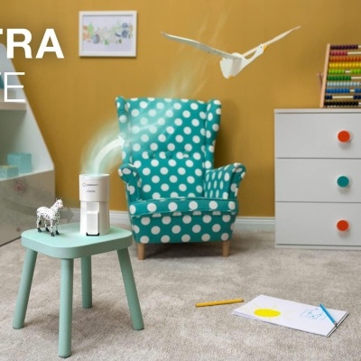 Cadeira azul com bolinhas, mesa verde com dispositivo, cómoda branca com puxadores coloridos e texto ULTRA SAFE.