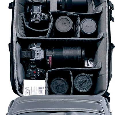 Mochila cinzenta aberta com câmaras, objetivas e acessórios fotográficos organizados internamente