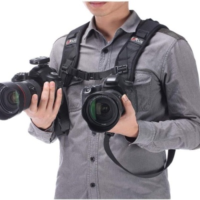 Homem com duas câmeras negras e arnês preto