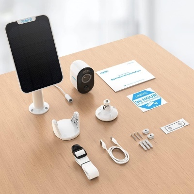 Conjunto de vigilância realink com câmara, painel solar, acessórios e etiquetas sobre mesa clara