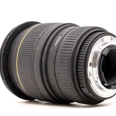 Objetiva fotográfica preta com detalhes metálicos e anéis texturizados em fundo branco