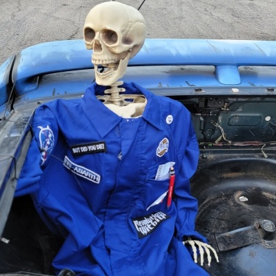 Esqueleto vestido com fato azul em carro descapotável azul