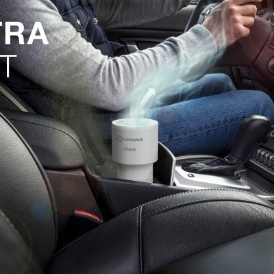 Frasco branco de aroma na consola de carro entre bancos em pele preta