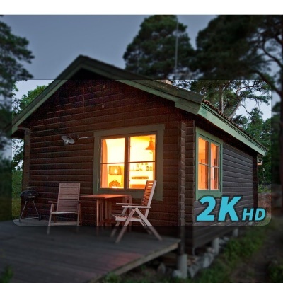 Cabana de madeira escura com janelas iluminadas e mobiliário exterior
