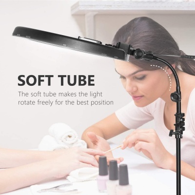 Luz de mesa preta flexível usada numa sessão de manicure com frascos de verniz e toalhas brancas