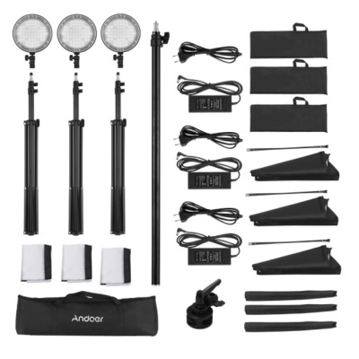 Conjunto de iluminação profissional com luzes LED, tripés e acessórios organizados numa superfície branca