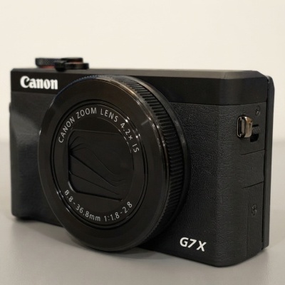 Máquina fotográfica digital Canon G7X preta sobre superfície neutra