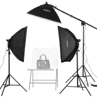 Conjunto de iluminação fotográfica com bolsa cinzenta sobre mesa branca.