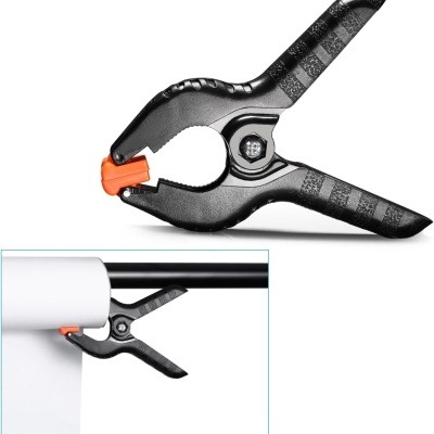 Mola de aperto preta com ponta laranja num suporte de barra com cortina branca