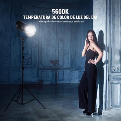 Estúdio com luz artificial e mulher vestida de preto encostada na parede azul