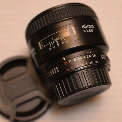 Lente fotográfica preta 85mm 1:1.8D com tampa num fundo claro