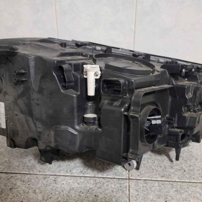 Farol automóvel preto em plástico com ligação elétrica numa superfície de azulejos