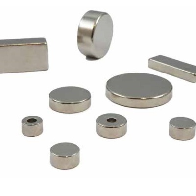 Ímanes metálicos pequenos de várias formas sobre superfície branca