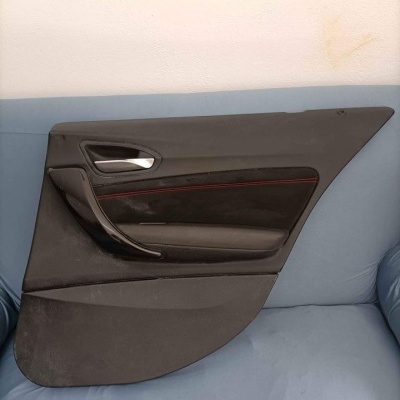 Painel interior de porta de carro preto com detalhes vermelhos sobre sofá azul