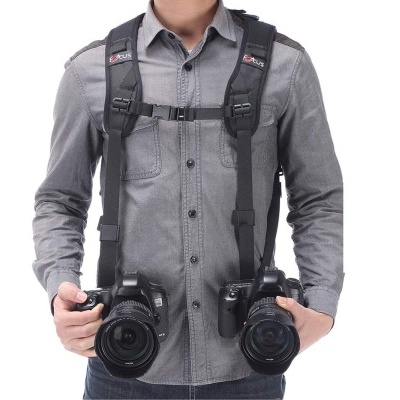 Homem com duas câmaras fotográficas digitais e alças pretas
