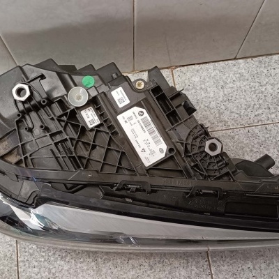 Farol automóvel de plástico preto e vidro transparente em chão de azulejo cinzento