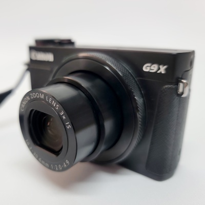 Máquina fotográfica Canon preta G9X com lente zoom 3x em fundo branco