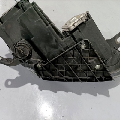 Peça automóvel preta com parafusos sobre superfície branca