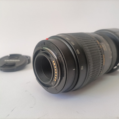 Objetiva fotográfica Tamron preta com marcas de distância focal de 70 a 180 e tampa ao lado