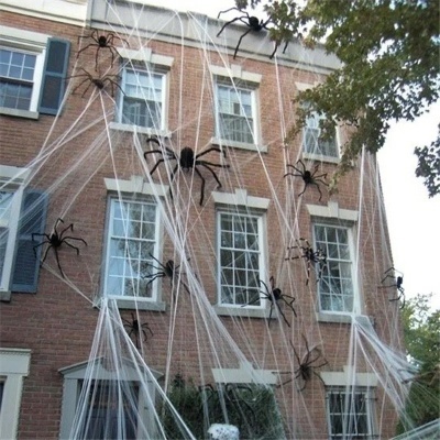 Decoração de Halloween com teias artificiais e aranhas pretas na fachada de uma casa