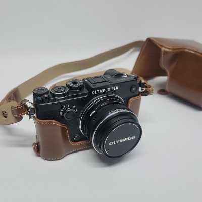 Câmara Olympus PEN preta com lente e capa em couro castanho