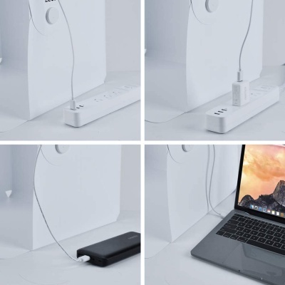 Cabo USB-C branco ligado a torre de computador, régua de tomadas, adaptador, power bank e portátil cinzento.