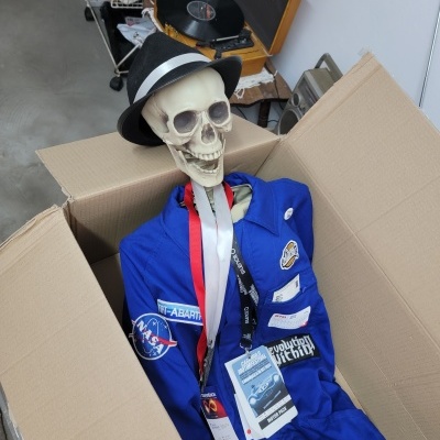 Esqueleto com fato azul e chapéu dentro de caixa de cartão