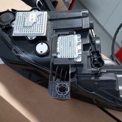 Componente automóvel preto com módulos eletrónicos metálicos sobre caixa de cartão