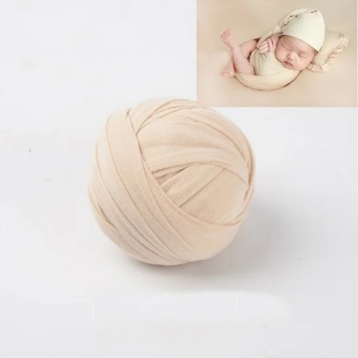 Bola de tecido bege com imagem de bebé enrolado no canto superior direito