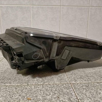 Farol de automóvel preto com lente transparente num chão de mosaico cinzento