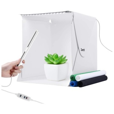 Mini estúdio fotográfico branco com luz LED e tecidos coloridos ao lado