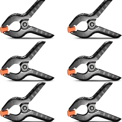 Seis molas de pressão pretas com pontas laranja sobre fundo branco