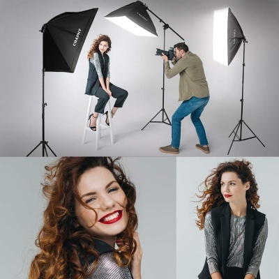 Mulher ruiva em sessão fotográfica com equipamento de iluminação e fotógrafo, vestindo colete preto e roupa prateada.