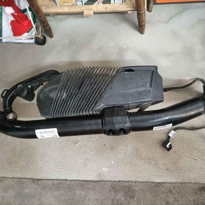 Peça automóvel preta sobre superfície têxtil cinza