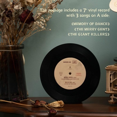 Disco de vinil preto com etiqueta bege em superfície de madeira junto a flores secas e decoração