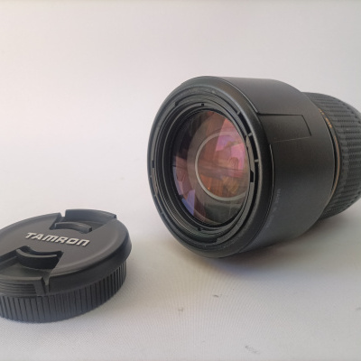 Objectiva fotográfica Tamron preta com tampa removida sobre fundo branco