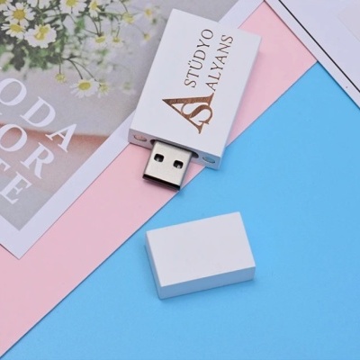 Pen drive branco com marca STÜDYO ALYANS sobre fundos coloridos e fotografia de flores