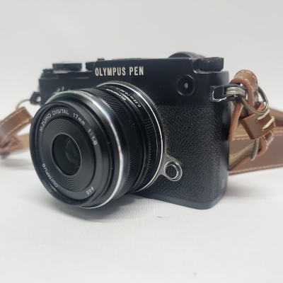 Câmara fotográfica Olympus PEN com lente 17mm e correia de couro castanho