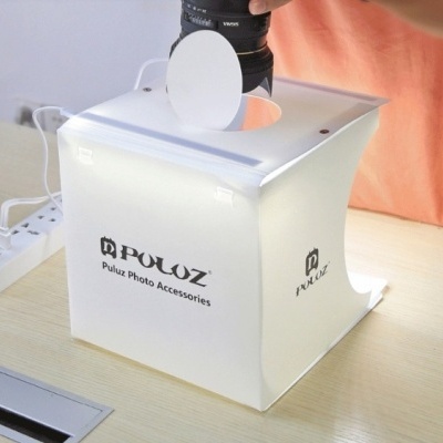 Caixa de fotografia branca POLOUZ sobre mesa com câmera fotográfica