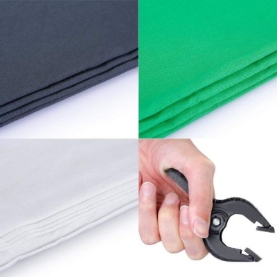 Tecidos cinza, verde, branco e mão segurando peça preta com agarrador