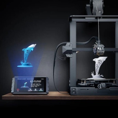 Impressora 3D preta a imprimir um golfinho branco com padrão de rede