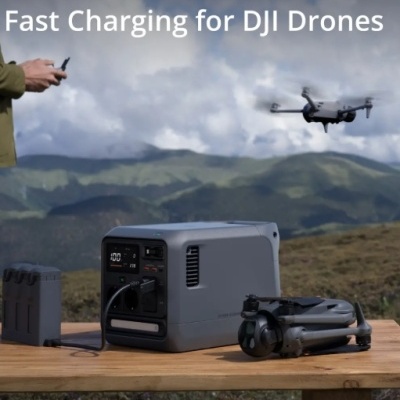 Estação portátil cinzenta, drone DJI cinzento e bateria numa mesa ao ar livre com montanhas de fundo
