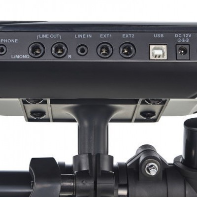 Dispositivo eletrônico preto com várias portas e rótulos montado numa estrutura preta