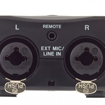 Dispositivo de áudio preto com entradas XLR/TRS e conexões auxiliares