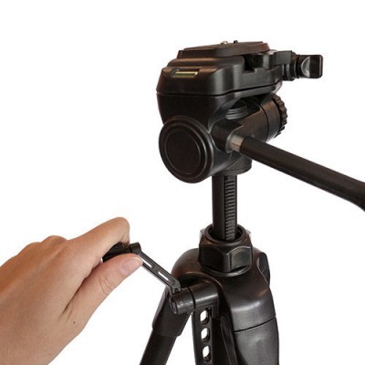 Tripé preto ajustável para câmara com mão a ajustar o aperto