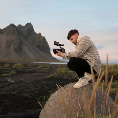 Homem a filmar natureza em rocha com roupa casual