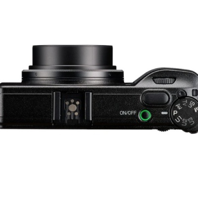 Câmara fotográfica digital preta vista de cima com botão ON/OFF e roda de modos.