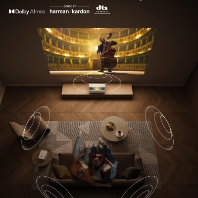 Sala de estar com sofá castanho, mesa de centro, tapete cinza e sistema de som Harman Kardon com áudio envolvente