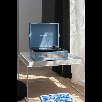 toca-discos portátil azul em forma de mala em mesa branca perto de janela com cortinas brancas