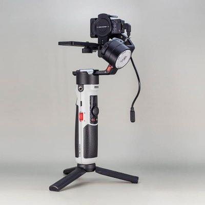 Estabilizador de câmera profissional preto e cinza com botões vermelhos em fundo cinzento